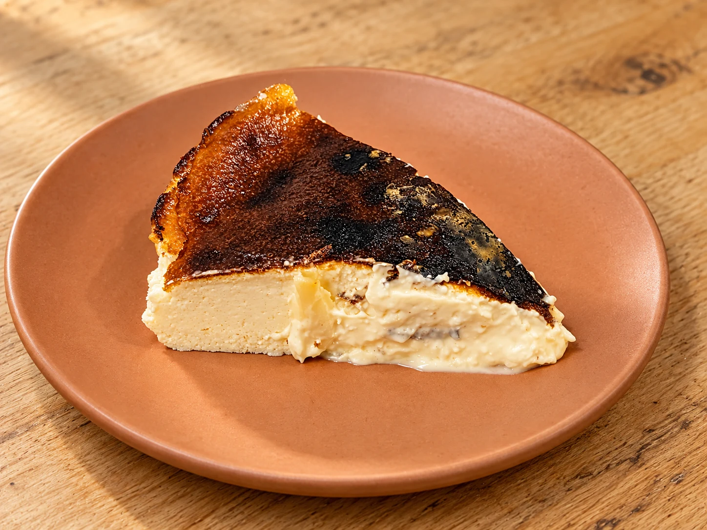 Porción de tarta vasca de Chucho Perdido con interior cremoso sobre plato de terracota